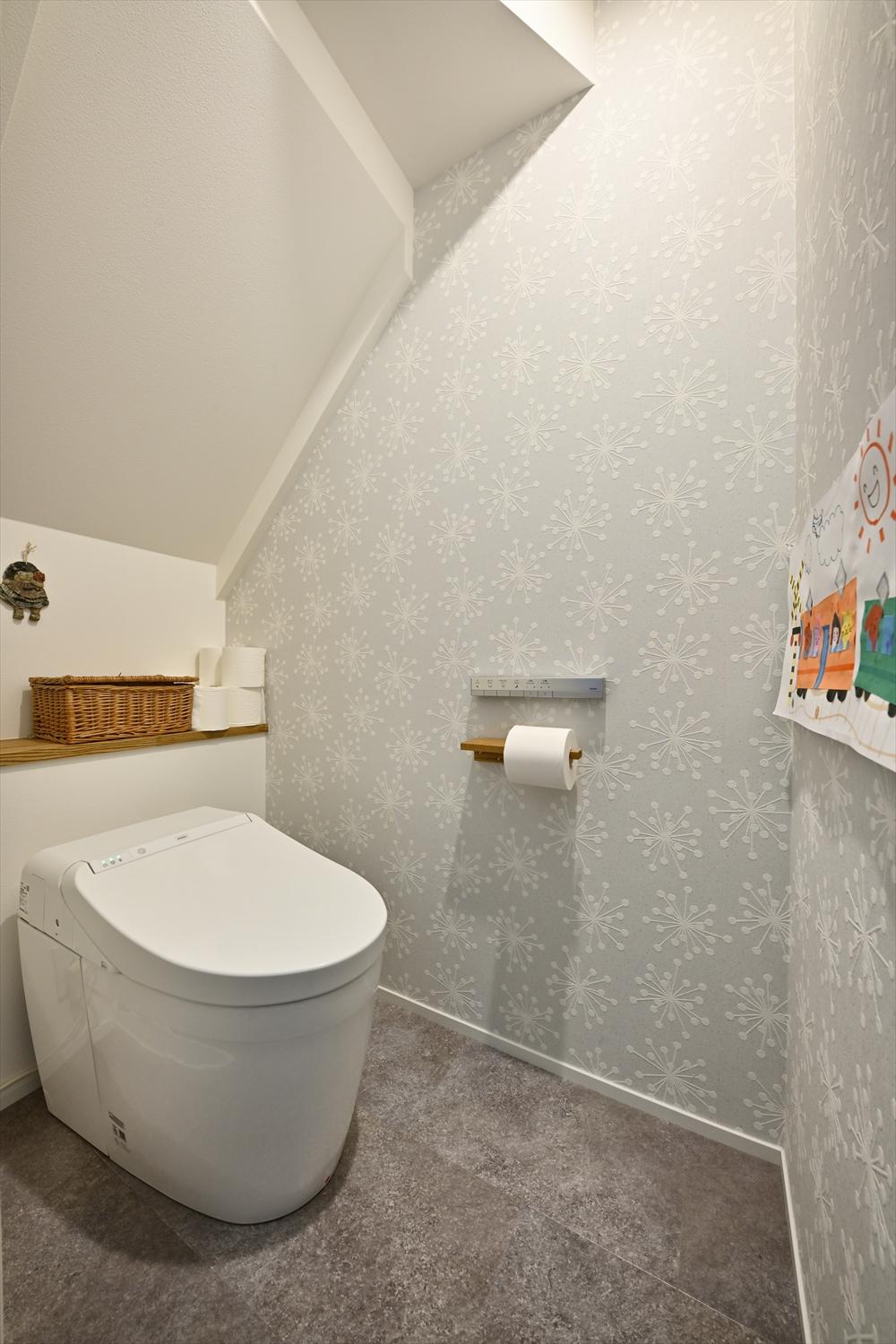 空間を有効活用するため、階段下に設けた１階のトイレ。お手入れしやすいフロアタイルと心癒されるアクセントクロスで仕上げた