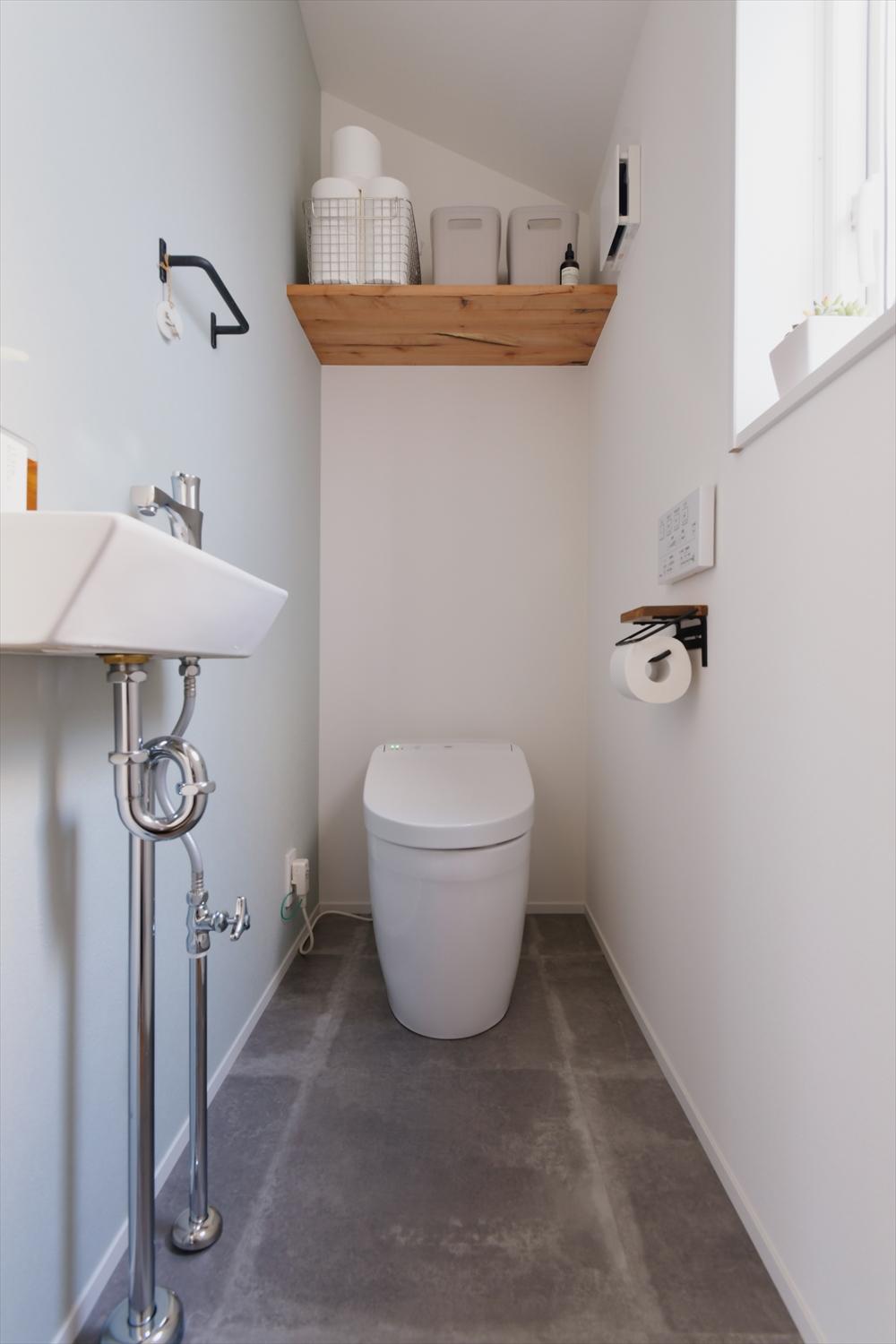 お手洗いの壁は一面だけ明るい水色のアクセントクロスで爽やかな印象に。シンプルな空間