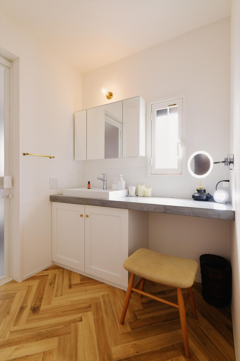 プライベート空間にある、メインの洗面室。造作の洗面台は天板にモルタル風左官塗装材のモールテックスを使用。収納の取手やタオル掛けは真鍮。お住まい全体のインテリアと合わせた