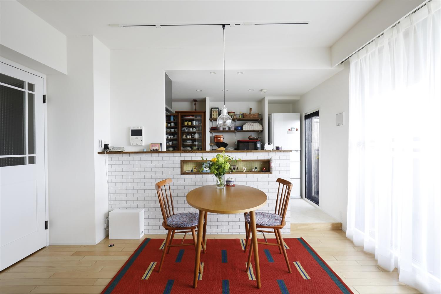 壁付けだったキッチンを対面式に。キッチンカウンターはタイル貼りで、お気に入りの雑貨や絵本を飾るニッチを作った。白をベースに、カーペットや家具、雑貨が彩る空間。