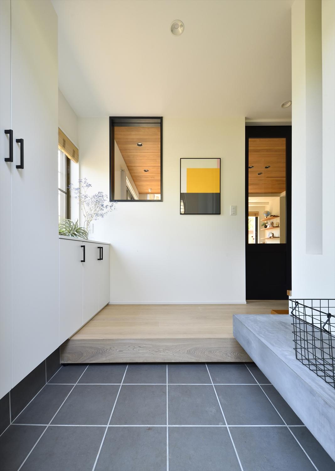 リビング側と室内窓でつながる玄関。リビングからの光も入り明るく心地よい空間。