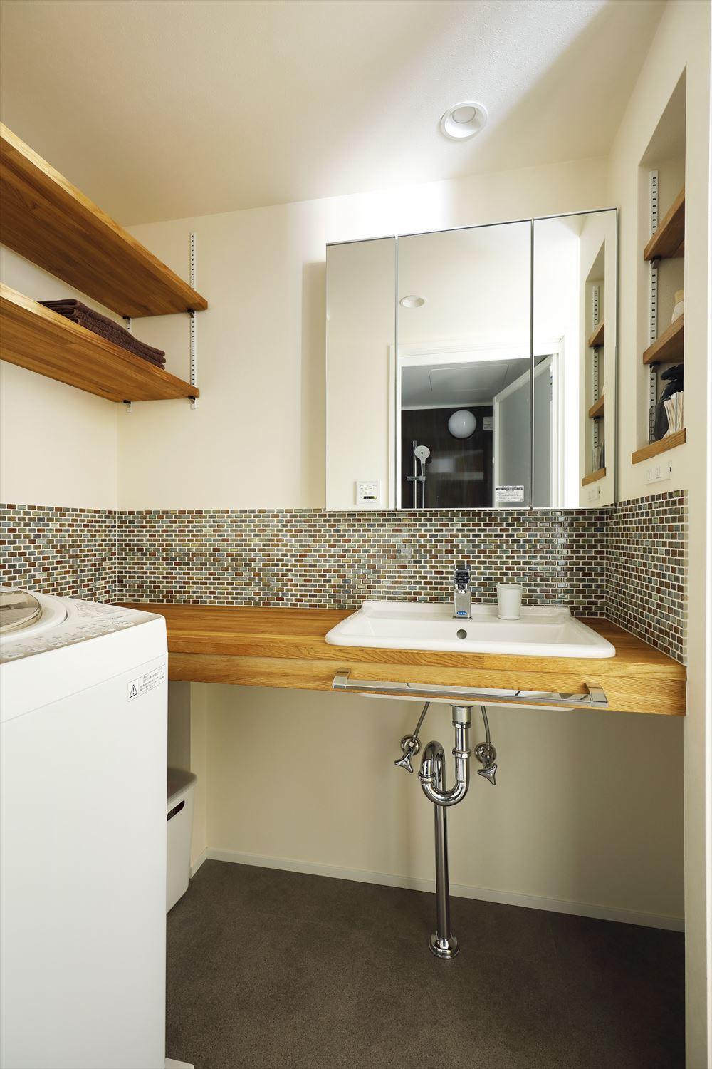 洗面はスッキリとシンプルな洗面台に。その分、収納機能のある鏡や隣のニッチ、可動棚で洗面周りのものを収納できる工夫をしている。