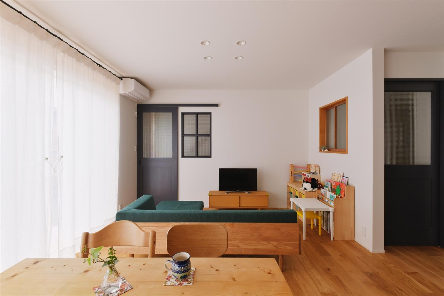 キッチン側から見たリビング・ダイニング。右手ドアの向こうが玄関、左奥のドアの向こうは階段へ。