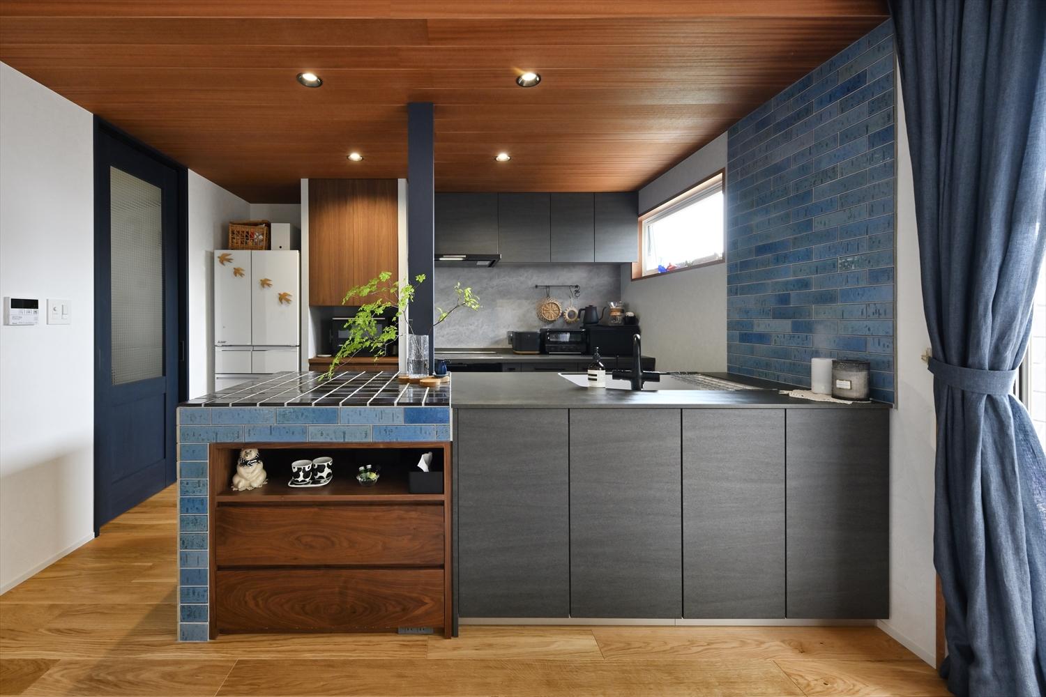 ブルーやグレーでまとめたキッチン。フローリングや板張りの天井の深い木目が馴染み、シックで落ち着いた雰囲気に。