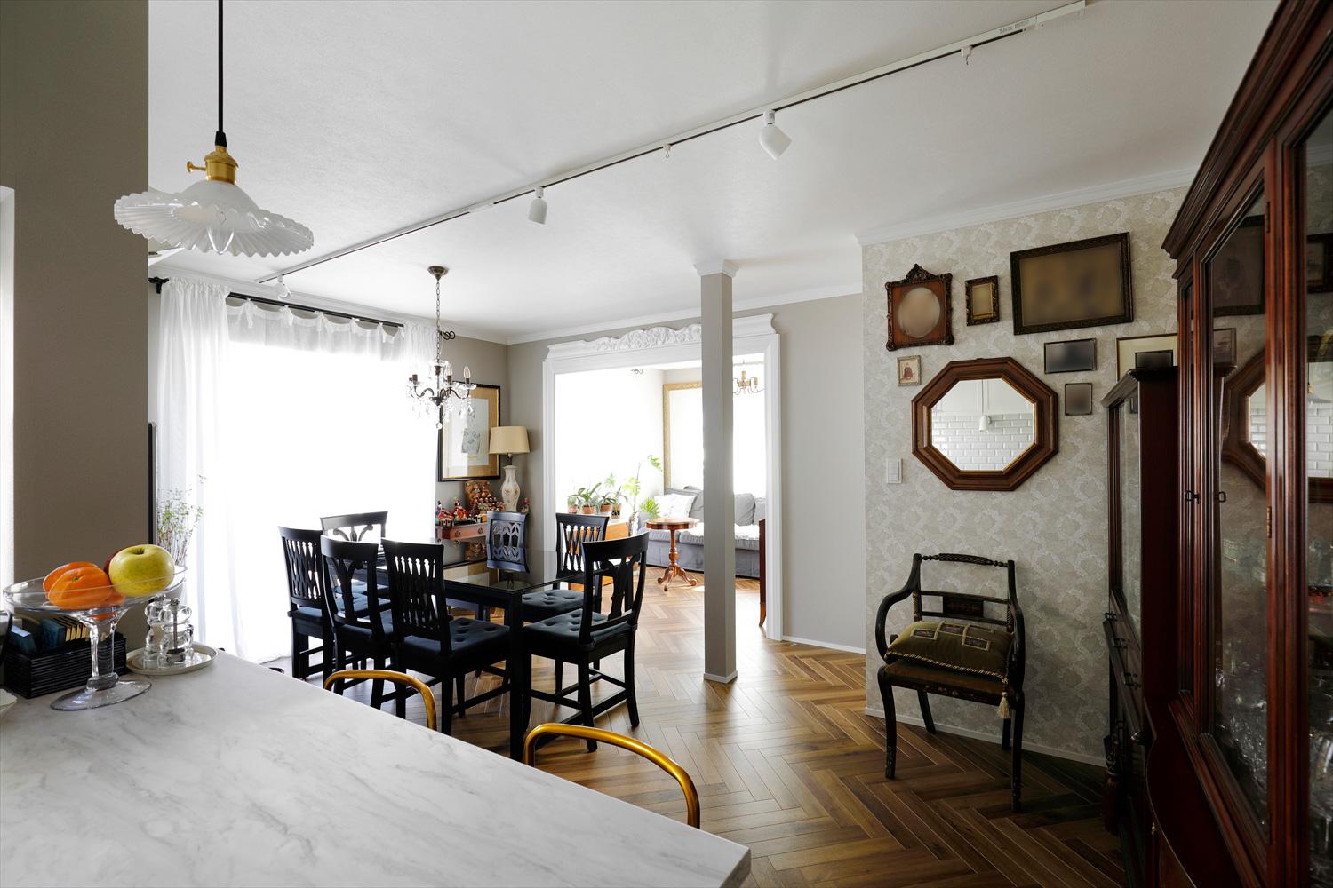 独立していた隣の和室を既存のリビング・ダイニングにつなげて、広々とした空間を確保。６人がけのダイニングテーブルを置いてもゆとりのあるダイニングとソファでくつろげるリビング。ウィリアム・モリスのデザインクロスとヘリンボーン、コレクションのアンティークでヨーロピアンクラシックな雰囲気に