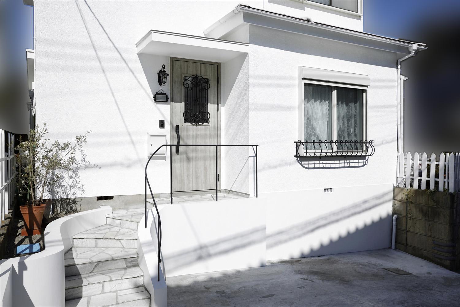 真っ白に塗り替えた外壁とアイアンの手すりのあるまわり階段でご希望の南仏風に。車が止めづらかった駐車スペースは門柱を撤去して広げ、入りやすく安全なアプローチに