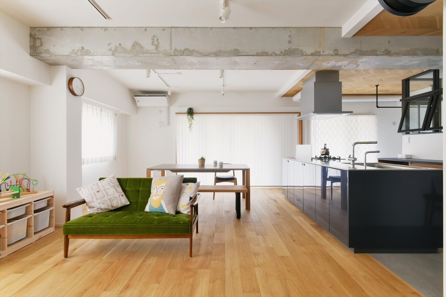 スラブを現しにしたラフな雰囲気の天井とオークの無垢フローリングが調和する広々LDK。キッチンや室内窓の黒が空間を引き締めている