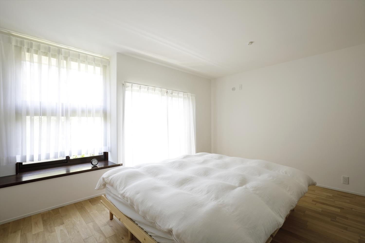 リビング奥の扉からつながる寝室。カーペット敷きだった洋室の床を足ざわりの良い無垢のフローリングに交換。たっぷりの日差しとともに心地よく目覚められる