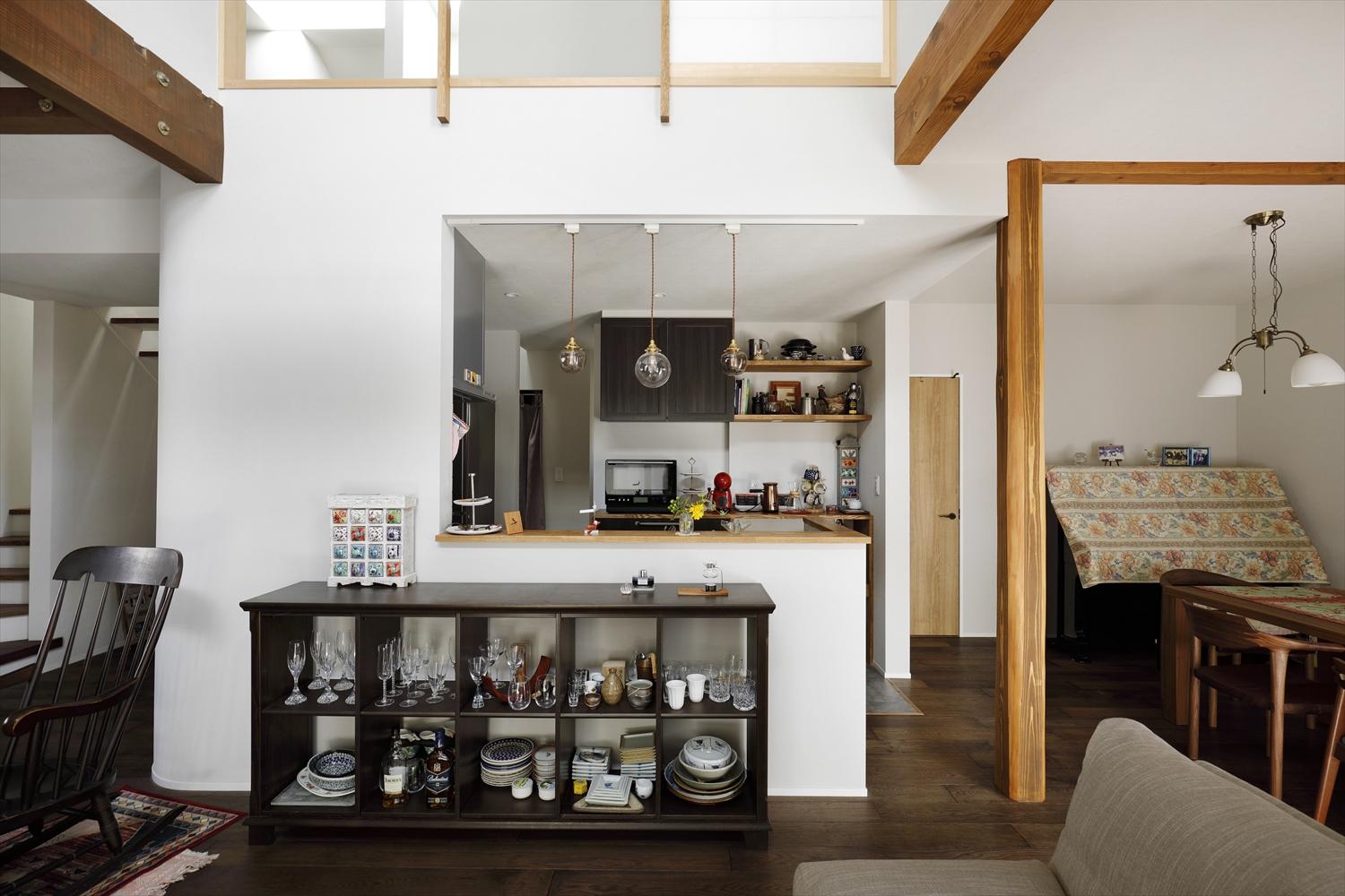 対面キッチンを1階のほぼ中心にレイアウト。手元が見えない立ち上がりを設けてスッキリ見せ、背面収納もオープンスタイルにすることで圧迫感をなくした。収納横の開口の奥にはパントリーがあり、水廻りへもつながる。階段側はアール壁を採用して柔らかな雰囲気に