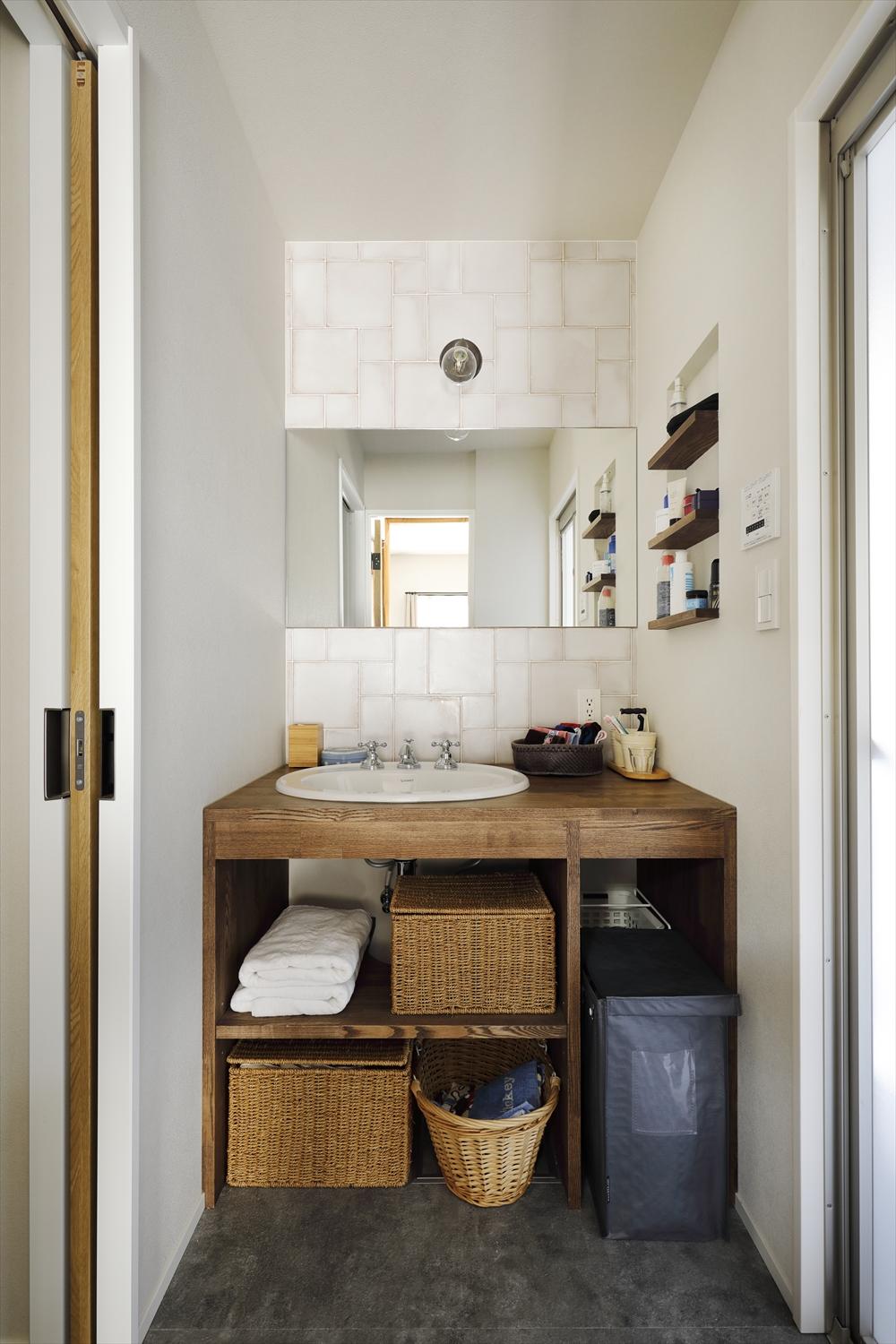 シンプルなデザインの木製洗面台に色ムラのあるタイルをプラスしてレトロな雰囲気を出した。キッチンや薪ストーブ周りのタイルなど、細かなアイテムも好きなテイストに仕上げている