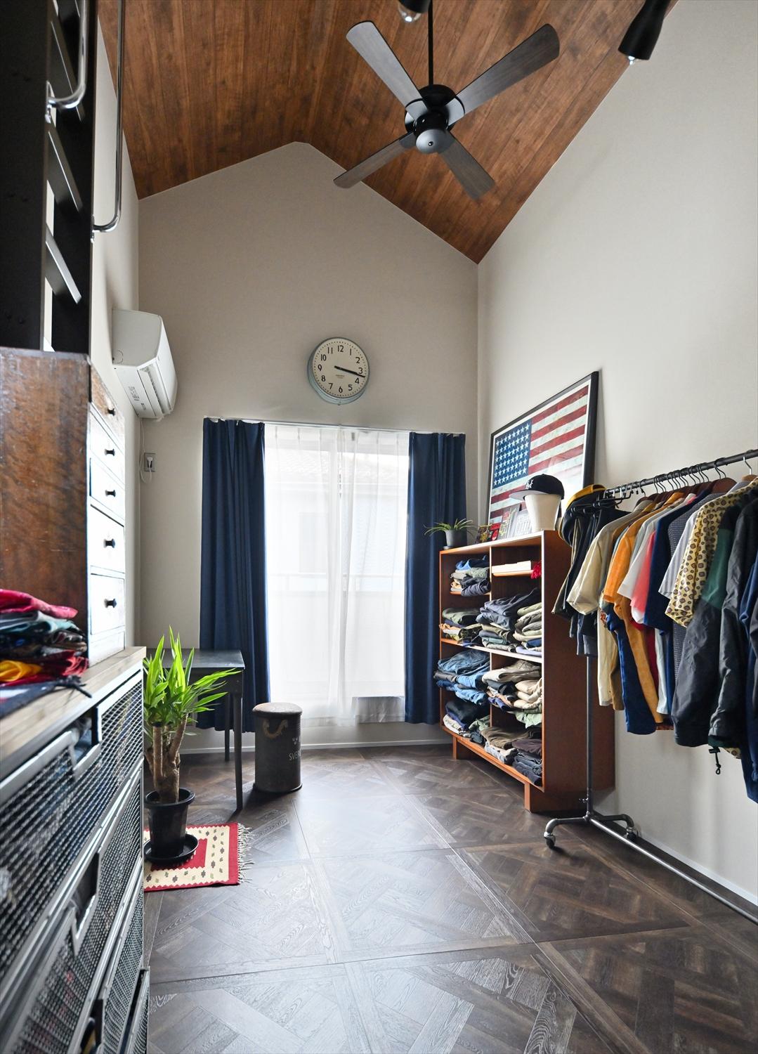 2階の趣味室。木目調のクロスを貼った天井と、パーケット風のフロアタイル、飾るように収納されたお洋服。まるで西海岸のお店のよう。