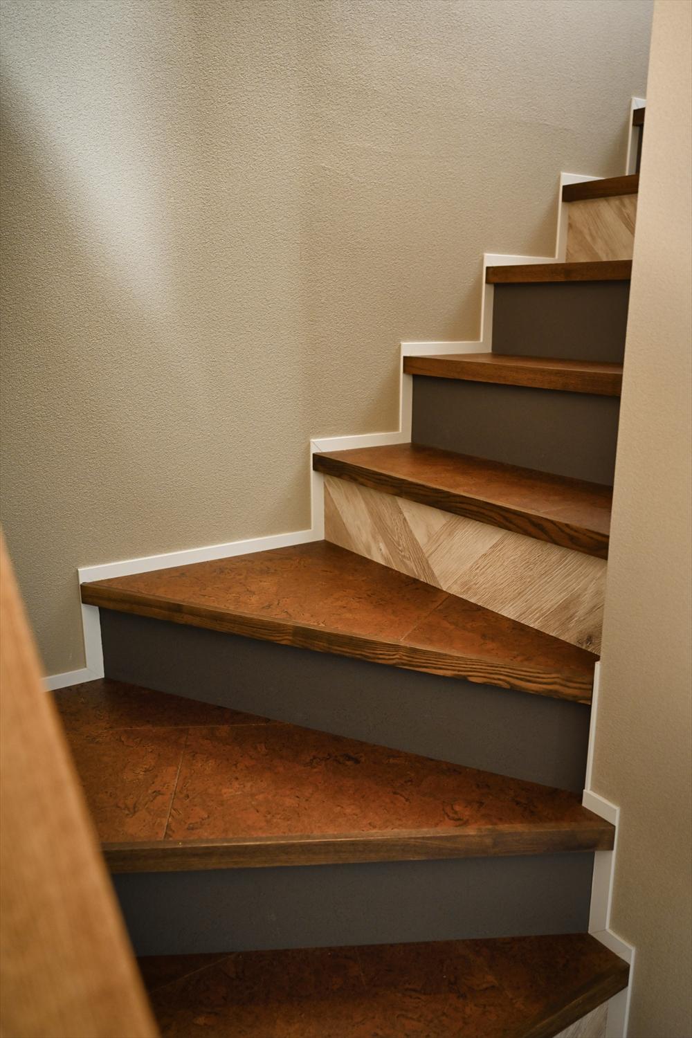 階段の蹴込部分はグレーのクロスの合間に木目調のクロスを入れるという遊び心を。