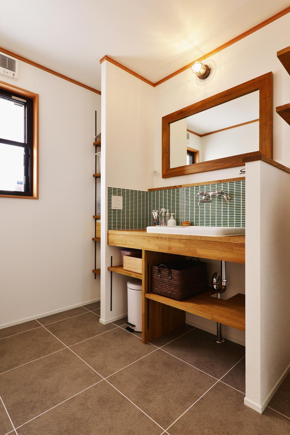 既存の洗面台を撤去して、タモ材とタイルを使った洗面カウンターを造作。洗面カウンターの奥にはオープンに収納できる可動棚も