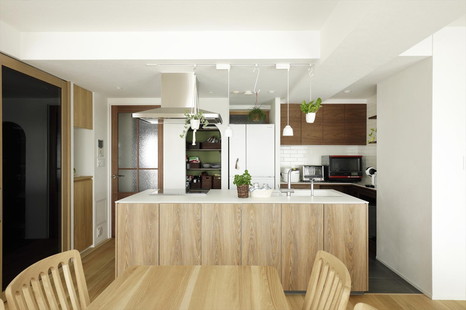 一方が壁についているペニンシュラ(半島)型からアイランド型に変えたキッチン。キッチン周りをぐるりと回れるようになって、使い勝手が向上。奥の壁、冷蔵庫の上に室内窓を設け、リビングの窓から入った風が窓のない玄間まで届くように。キッチンにも風が流れて心地よくなったそう