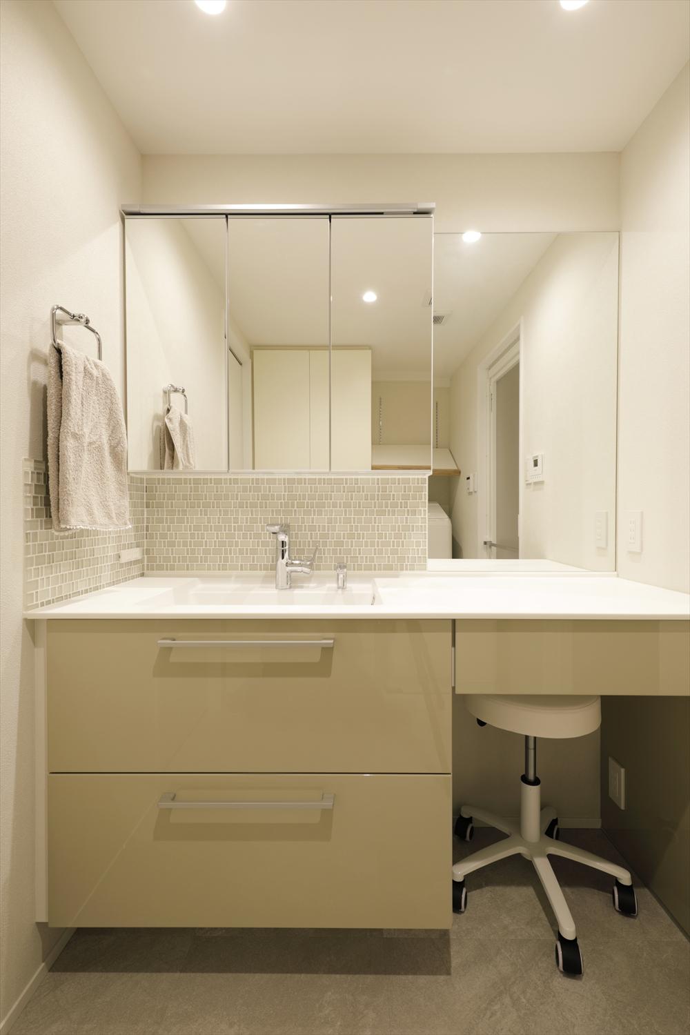 清潔感のある白で統一した洗面台。ゆったりしたカウンターと大きなミラー、スツールをおけるスペースでお出かけ前の準備もしやすくなった