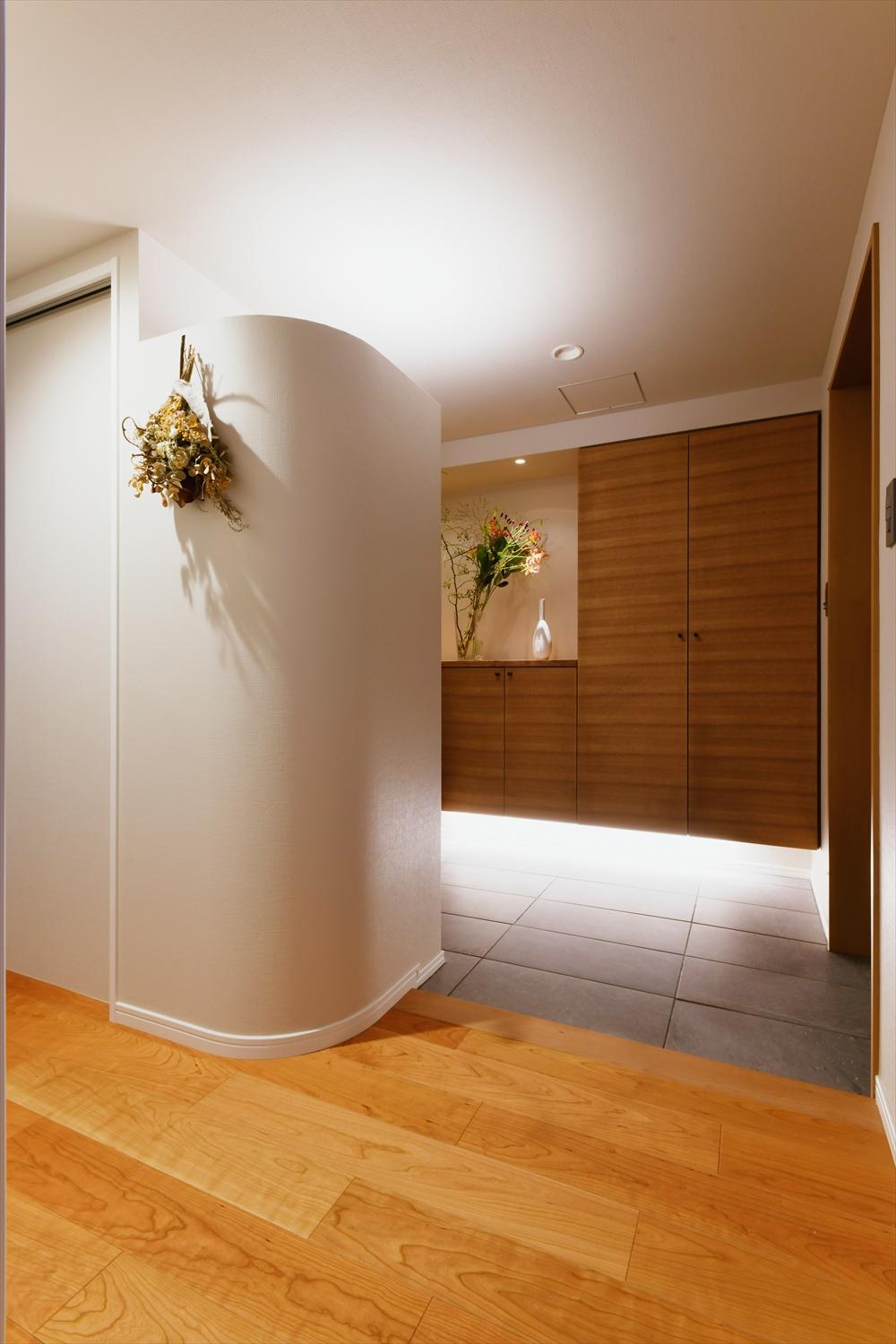 さりげない工夫④玄関横にあったマルチスペースを一部取り込んで、玄関自体を広げつつ、収納を浮かせて間接照明を設置。
より玄関を広く感じられる。Rの壁の向こうはコードなどをかけておけるクローク