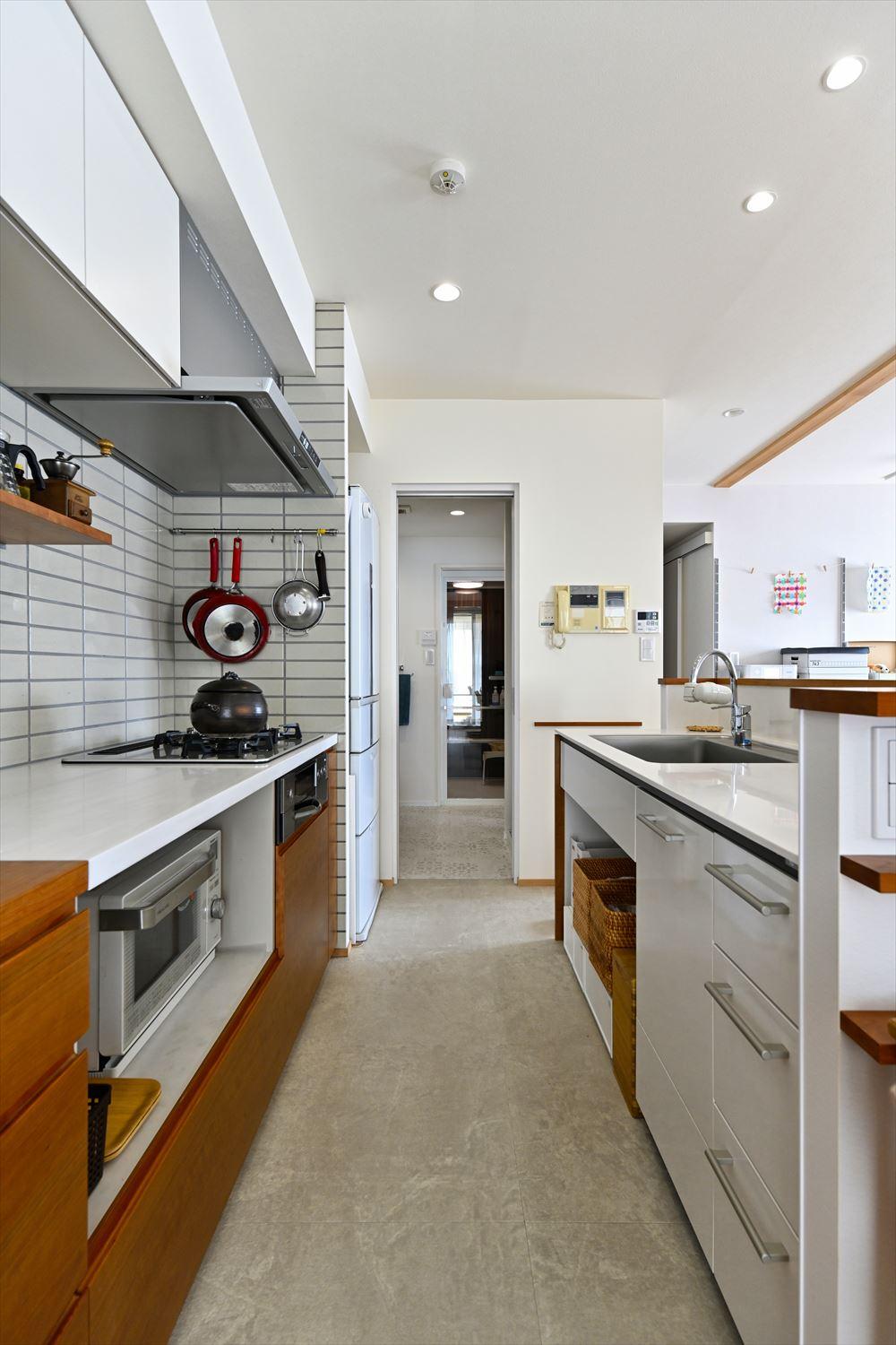 キッチンは壁側にコンロ、カウンター側にシンクのあるⅡ型を選択。リビング・ダイニングから見える位置にはサクラを使った造作収納も。キッチンからまっすぐ水回りにアクセスできる動線も嬉しい