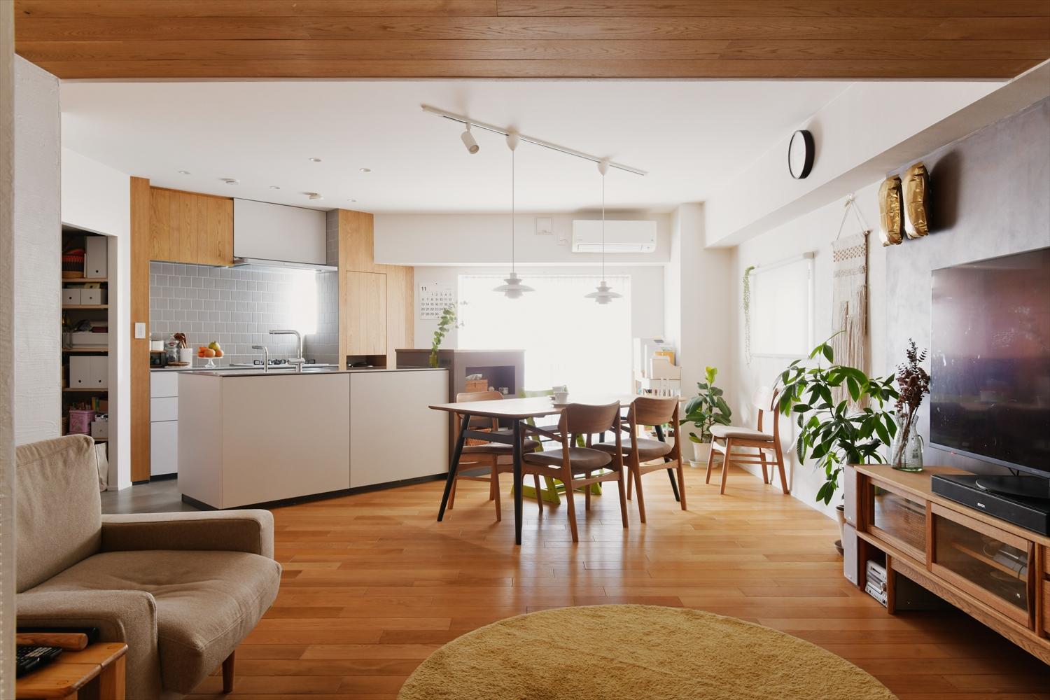 キッチンを斜めに配置したLDK。オークの無垢フローリングやタモ材を使用した収納などの木目と白を基調とした空間に仕上げた。