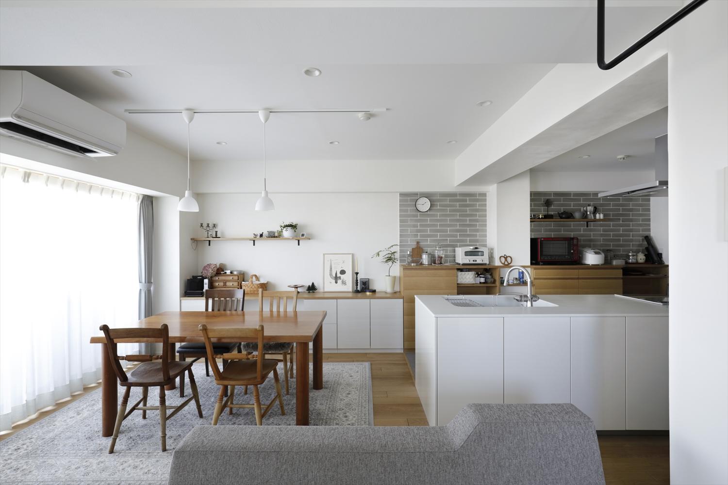 独立していたキッチンは壁を取り払って向きを変え、リビングに和室を取り込んでゆったりくつろげるLDKに。無垢フローリングと壁の一部に珪藻土を左官し、心地よい住空間を実現。キッチン背面のタイルやソファなど淡いグレーが上品で大人なインテリアをつくっている。