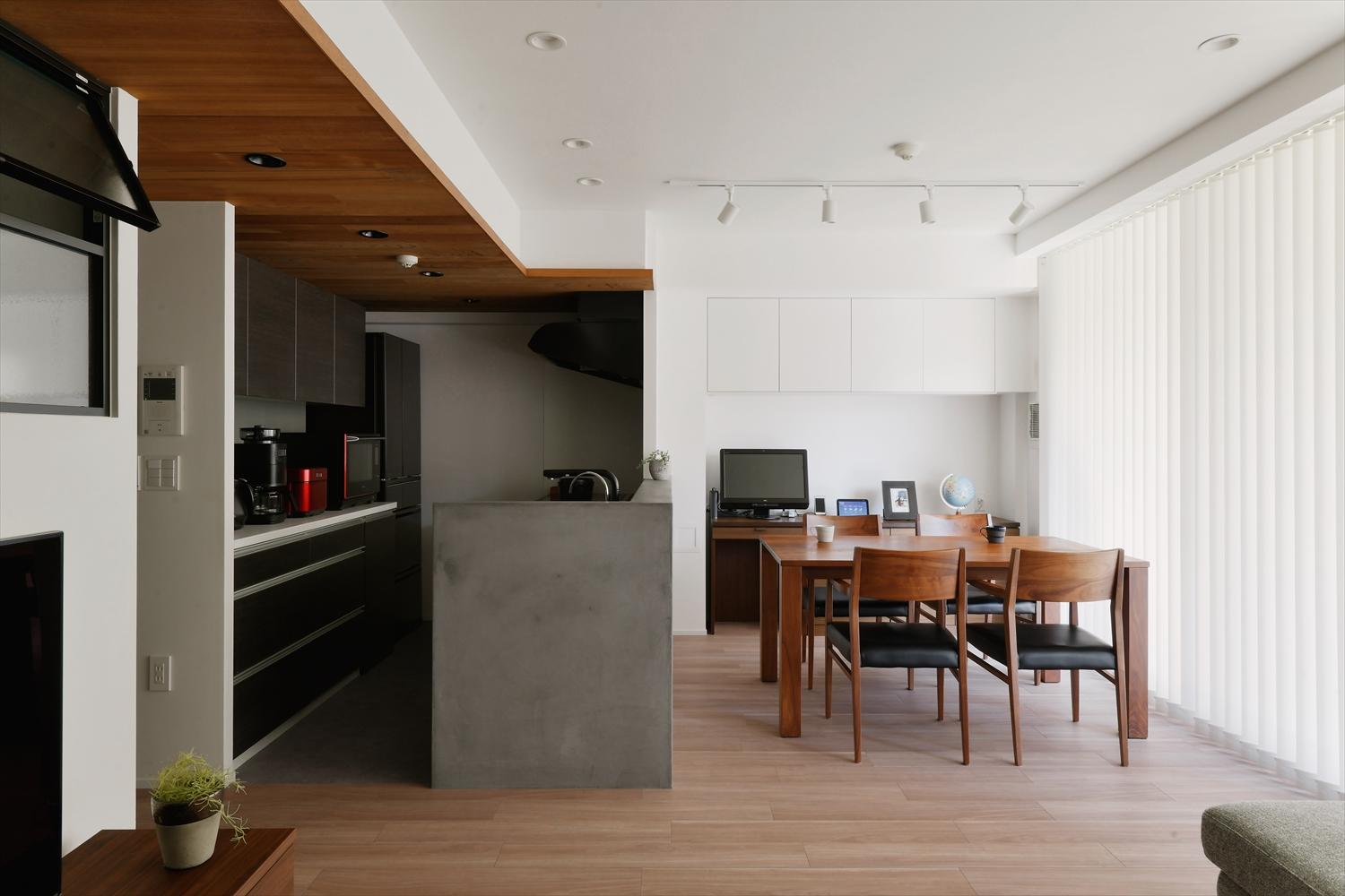 閉塞感のあったキッチンはダイニング側の吊り戸棚を撤去し、オープンに。ダイニング奥に新たに吊り戸棚を設置し、収納量を確保。モルタルのような質感を楽しめるモールテックスで仕上げたキッチンカウンターと板貼り天井がLDK全体のインテリアのベースになっている。