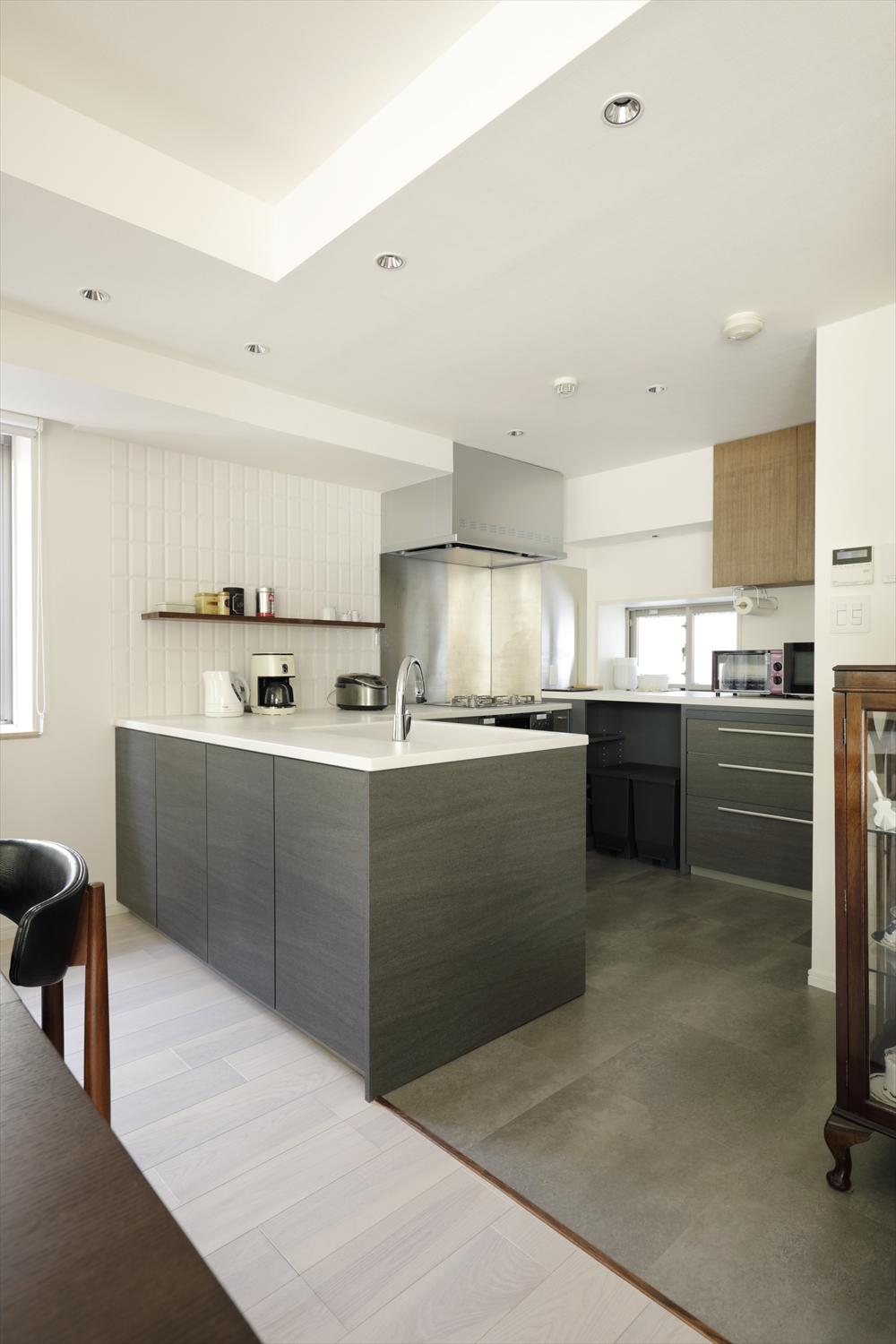 コンロを奥に配置したのは、ダイニング側への油はねを防ぐため。コンロ横にはデザイン・高さをキッチンと合わせたカウンター収納を造作。家電、食器の収納だけでなくゴミ箱位置までオープンだからこそスッキリと見えるよう、綿密に計画。