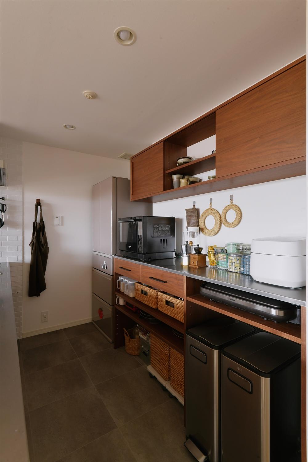 キッチンの背面にはキッチンに合わせたステンレスの天板と濃い色味の木材で素材感の違いを楽しめるカップボードを造作。家具職人による特注です。