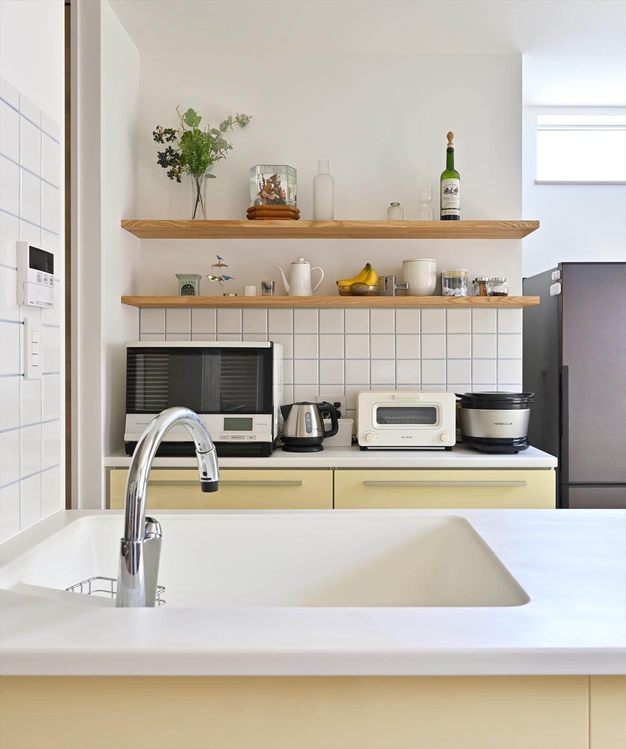 キッチン背面のカウンターと上部のオープン棚。左横の扉付収納と合わせて、見せる収納・隠す収納を便利に使い分け。