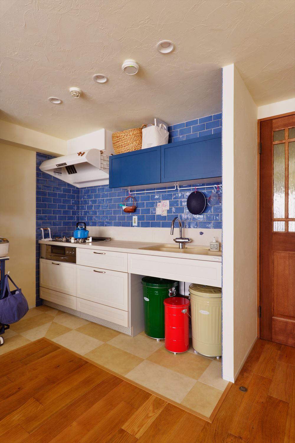 キッチン壁面はきれいな青色のタイル。お子さま手作りの手描きタイルもポイントに取り入れています。カウンター上部収納の扉も青色に。シンク下部には大きめのダストボックスがスッキリと収まります。