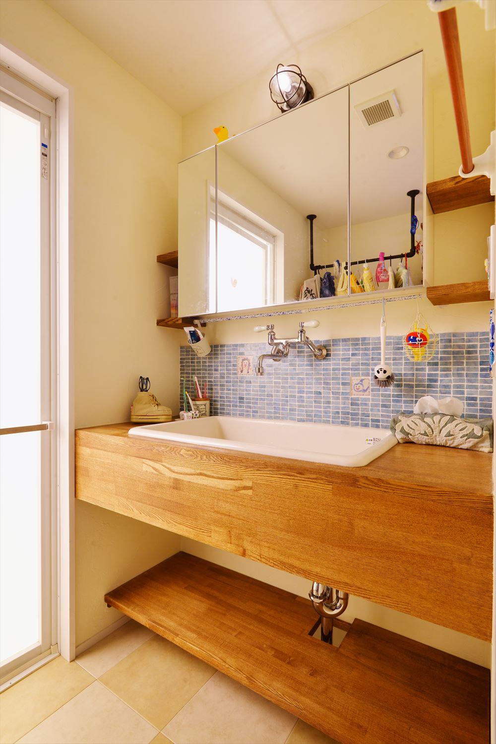 洗面台にも、キッチン同様、お子さまの手描きタイルが。木製カウンターとともに、あたたかな雰囲気を演出。