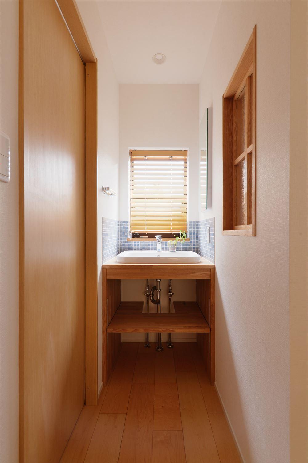 洗面台は造作。限られたスペースながら、外向きの窓とキッチン側への室内窓によって明るい空間になっています。