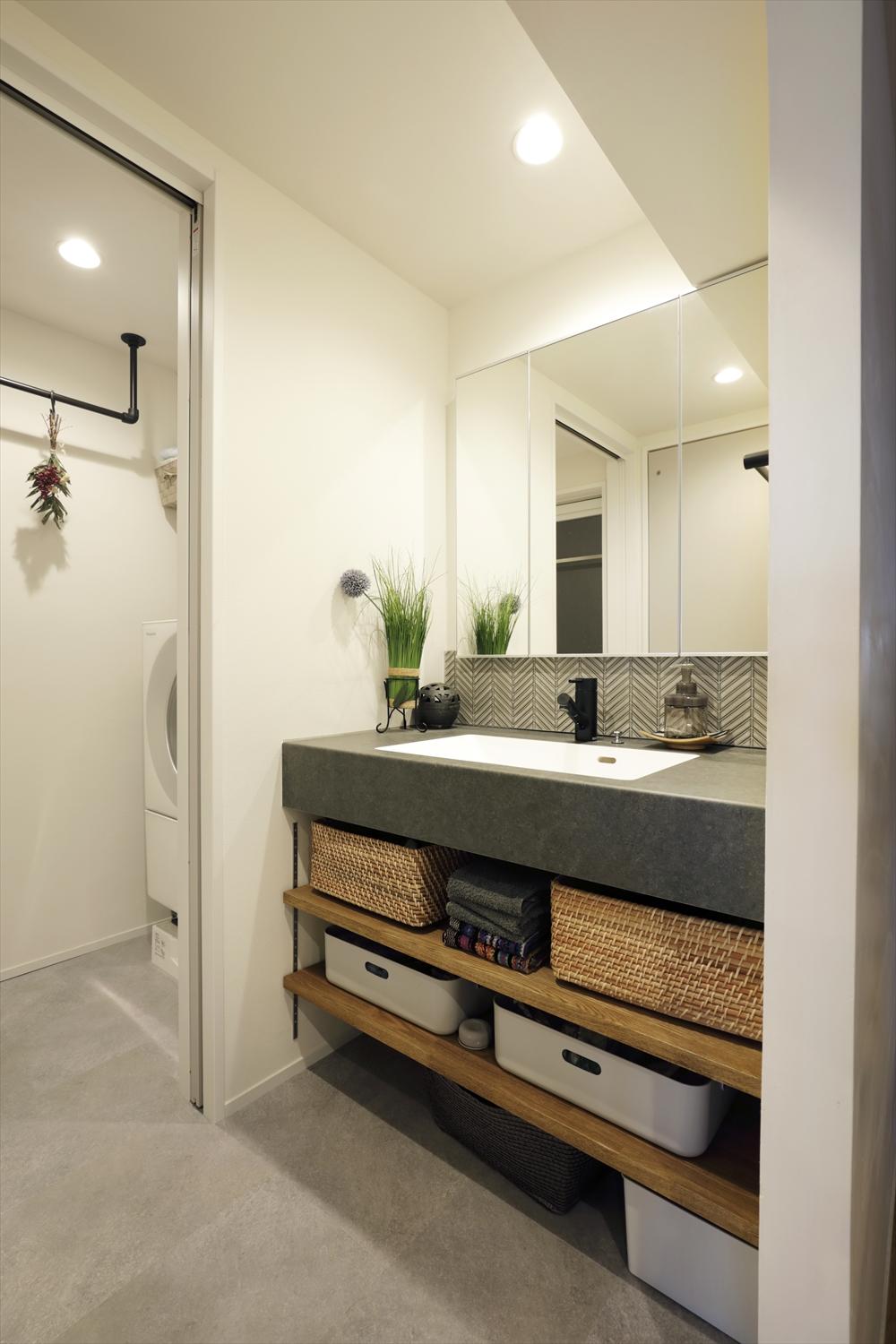 洗面台もクールな質感のものを採用。下部に棚板を設置し、収納にも便利。ミラー下部のヘリンボーン貼りのタイルにもこだわりが。