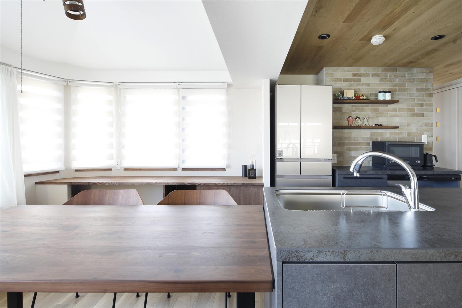 対面式のキッチン。背面の壁はニュアンスある色味のタイルで仕上げています。