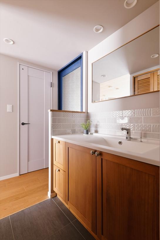 洗面所と廊下の間には扉や仕切りを設けず、オープンにして暗さや圧迫感を感じないように工夫しました。木目調の洗面台は隣接するキッチンの天井と呼応しています。