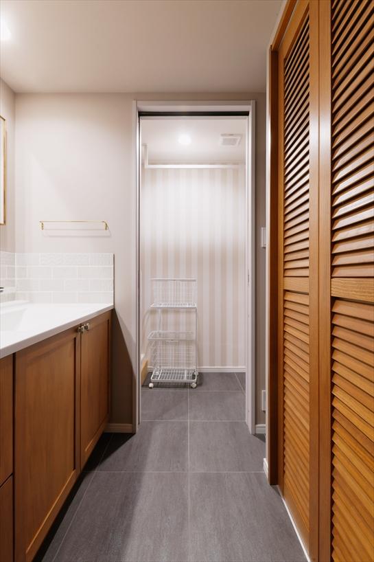 洗面台背面のリネン収納は、風通しの良いルーバー扉を採用。奥には引き戸のついた脱衣室。洗面所と脱衣室を分けることで、家族の入浴時も気軽に洗面所を使えます。