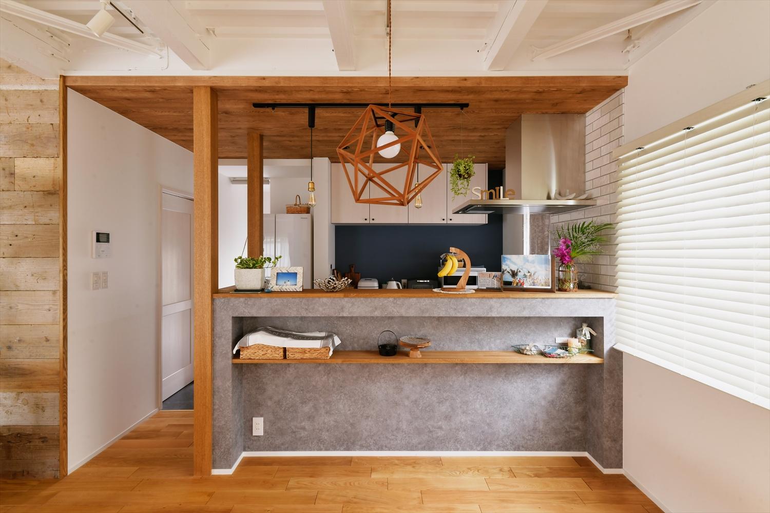 ダイニングと対面するキッチン。コンクリート風のキッチンカウンターがリビングダイニングのラフな雰囲気にマッチ。左奥の扉の先は、玄関とキッチン間をつなげる便利なバックヤード動線となっている。