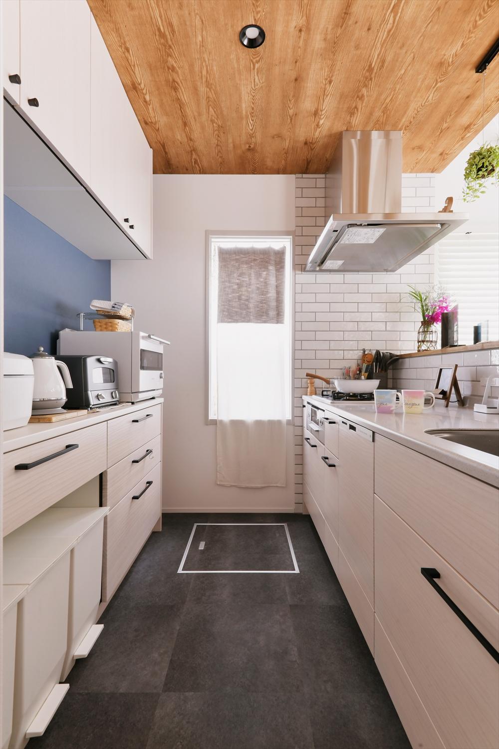 背面収納も充実したキッチン。リビングダイニングと変化をつけた板張り風の天井が、大空間をゆるやかにゾーニング。