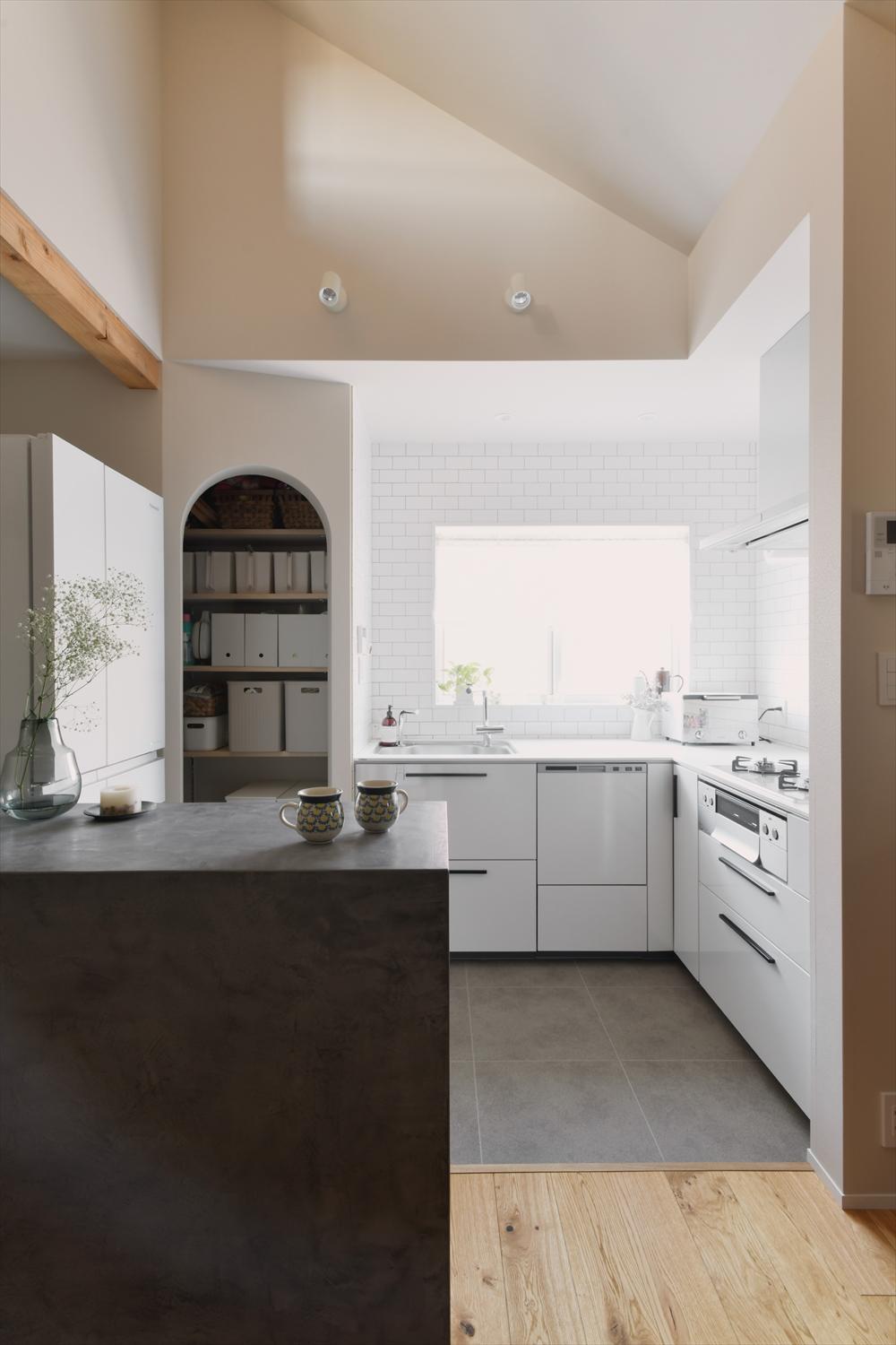 家族で使いやすいL字のキッチン。手前のモールテックスカウンター下部には収納棚が、さらにアーチ開口のパントリーもあって、オープンなキッチンもスッキリと見せられます。