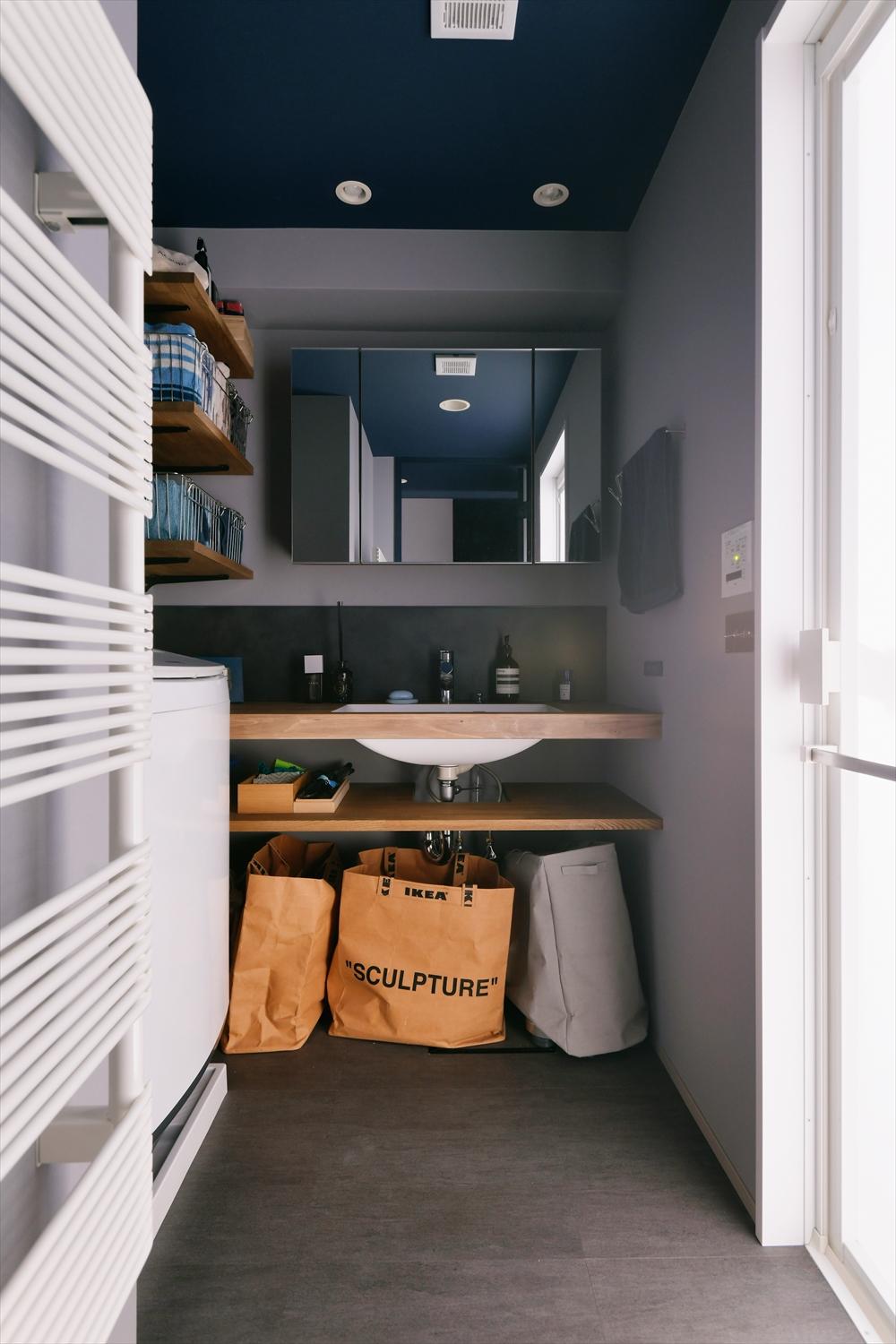 洗面室は洗面台をセミオーダー+造作ですっきりとさせお洒落な空間になり、収納はオープン棚にすることで出し入れがスムーズに。天井にテーマカラーのブルーをあしらっています。