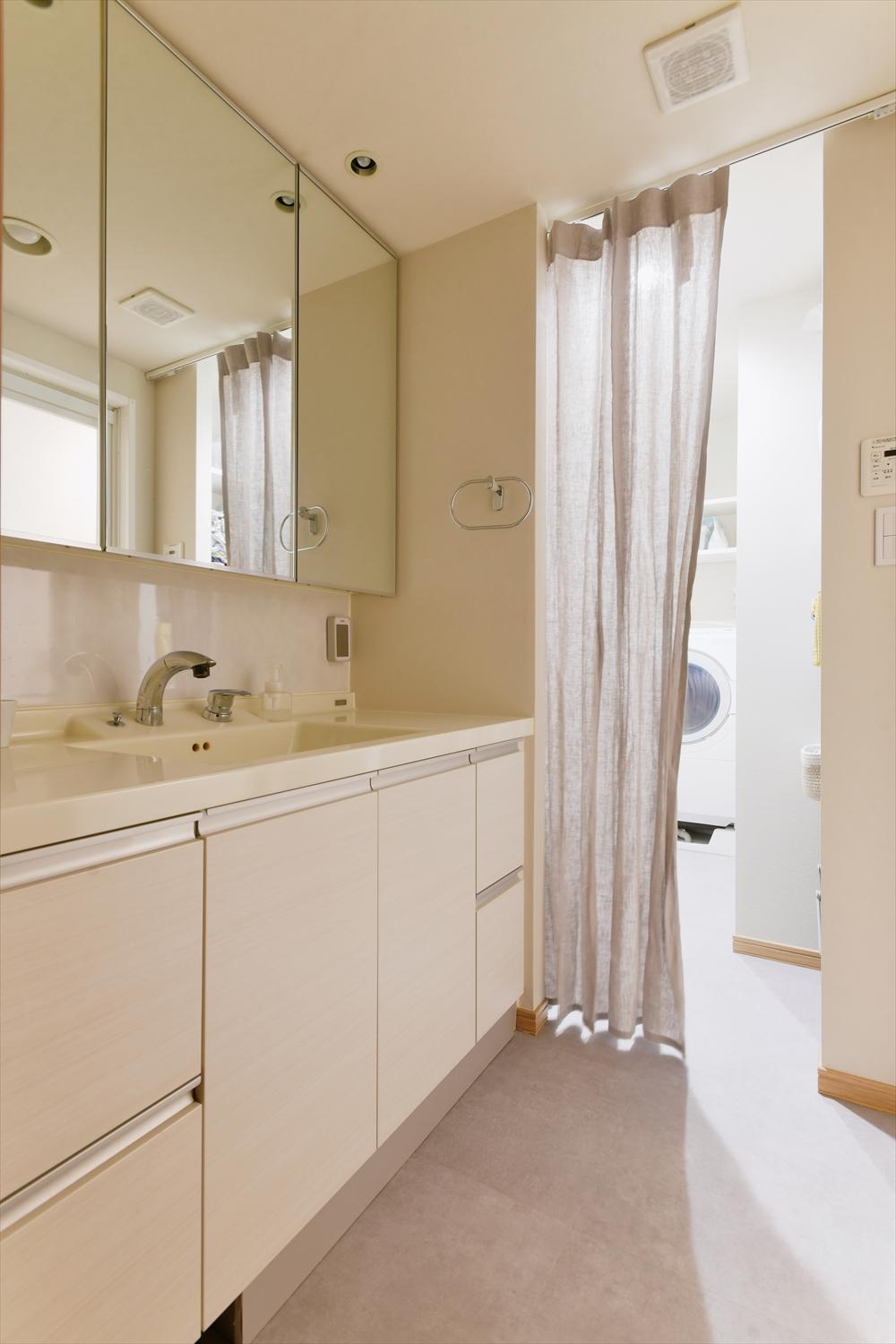 キッチンとダイレクトにつながる洗面・脱衣スペース。普段はオープンで通り抜けしやすく、入浴時はカーテンで間仕切りできるように。