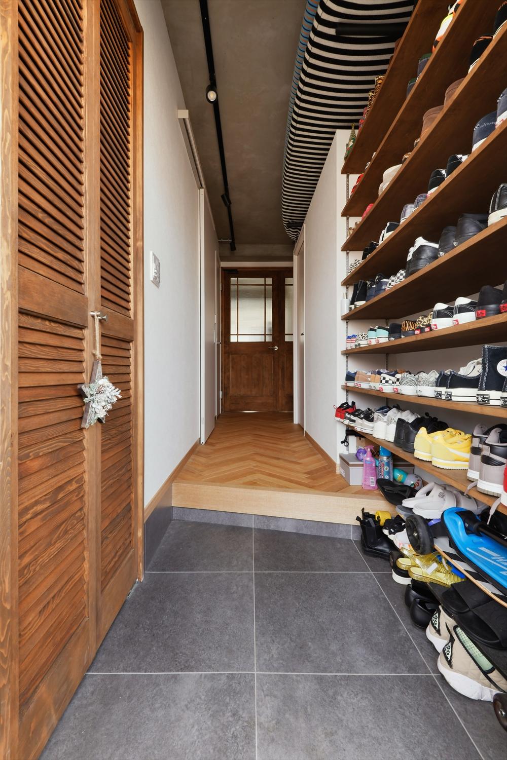 廊下と寝室を仕切る壁の上部にスペースを設け、サーフボードを置けるように工夫しました。立てかけると天井につかえてしまうような長さのボードも、うまく収納できます。
玄関の靴収納は可動棚をたくさん用意したオープンスタイルに。