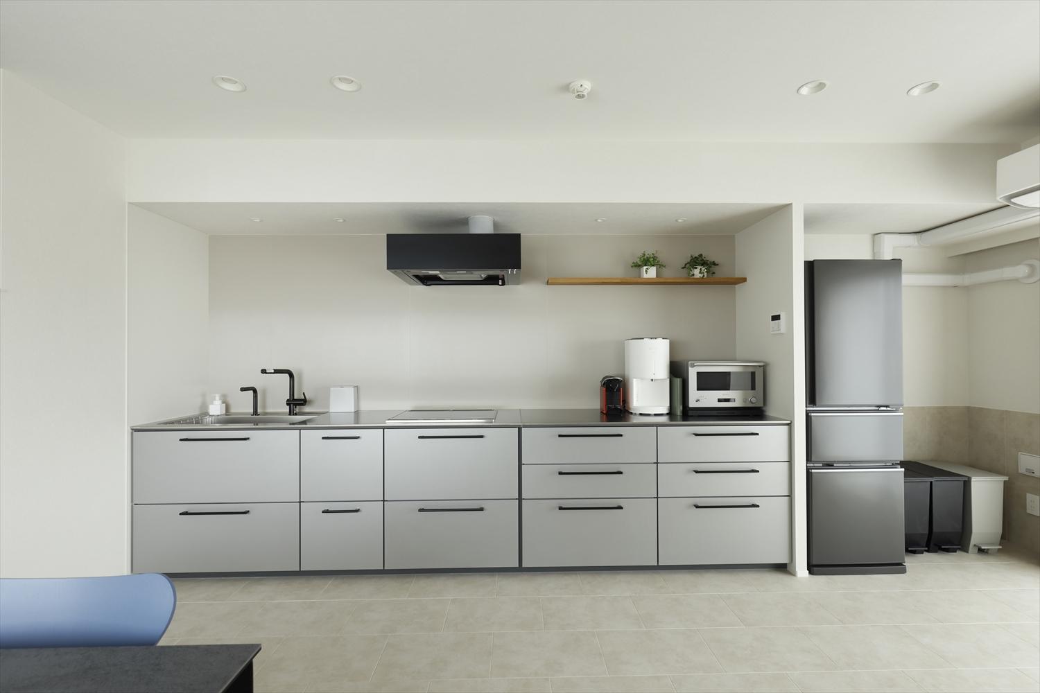 間口が限られていたため、広いLDKを確保するためにキッチンは壁側に寄せ、造り付けの家具に見えるよう幅めいっぱいまで広げました。キッチン用具以外のモノも収納することができるので、他の収納家具を置く必要がなくなり、よりスッキリとした空間に。