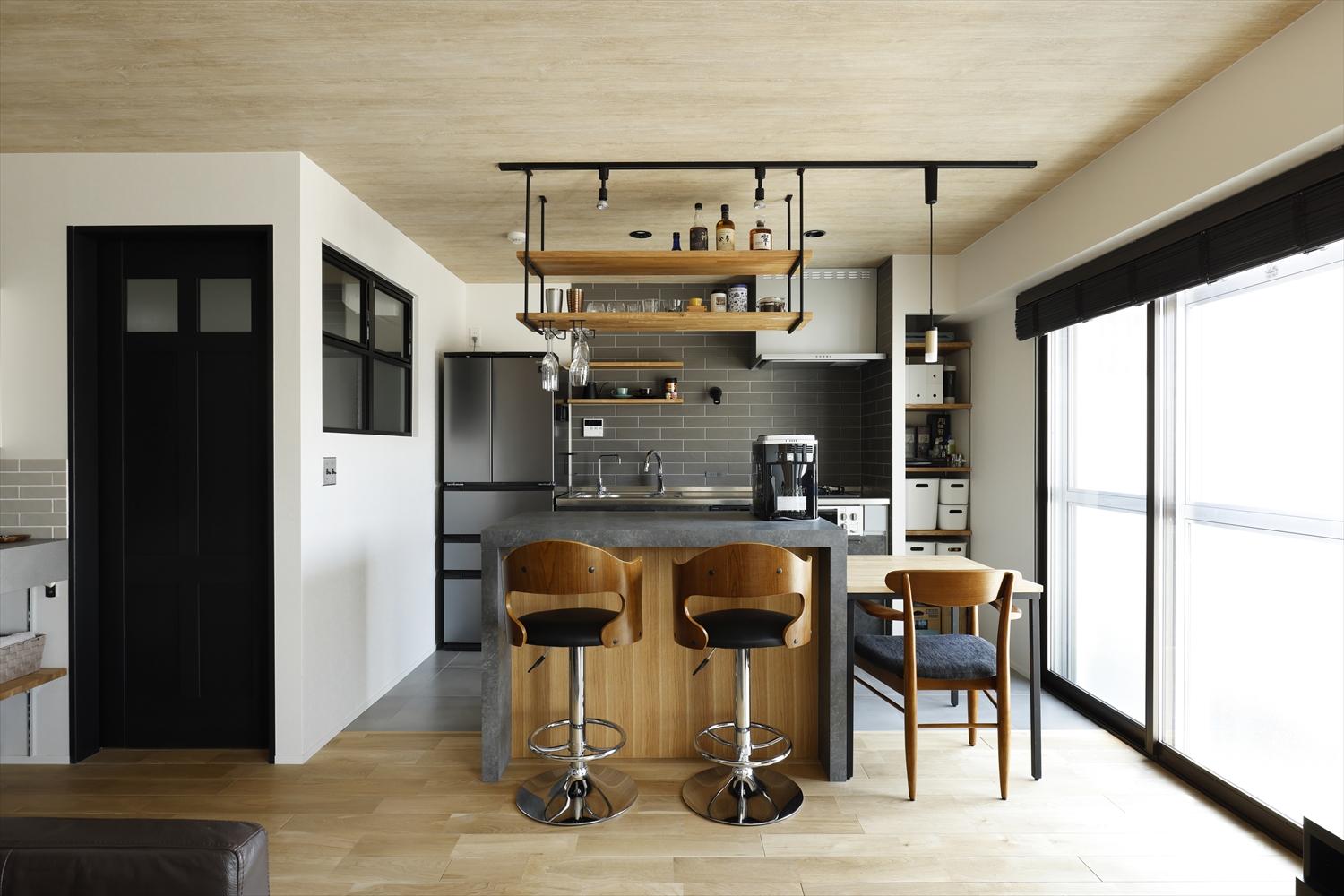 キッチンは壁付けとして、壁にはグレーのタイルを施しクールな雰囲気に。カウンターを造作し、ハイチェアに座ればお酒と景色を楽しめるバーカウンターとしても使えます。バーカウンターの内側を家電収納とすることで、リビング・ダイニング側からは家電が見えずスッキリとした印象に。