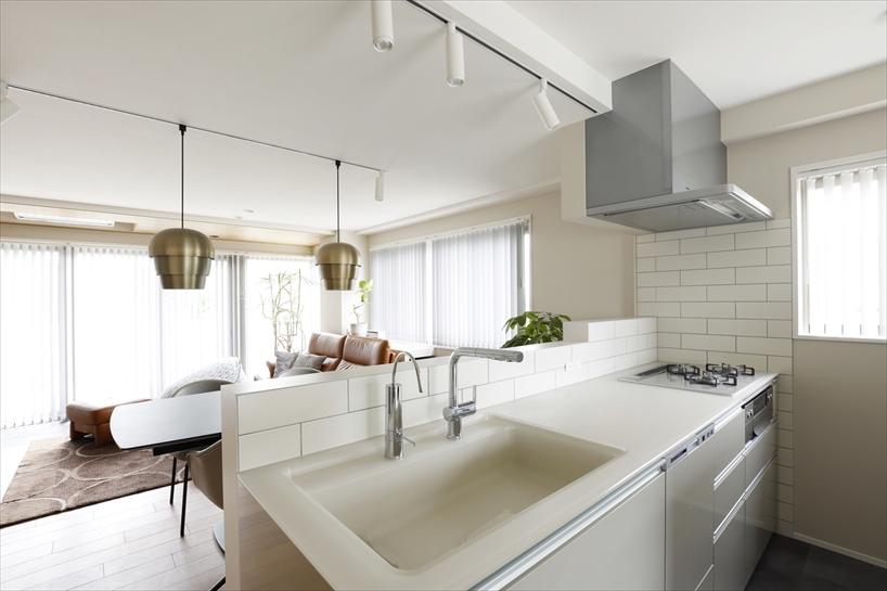 シャープなデザインのキッチンカウンターに合わせて壁や立ち上がりに清潔感のある白いタイルをあしらいました。