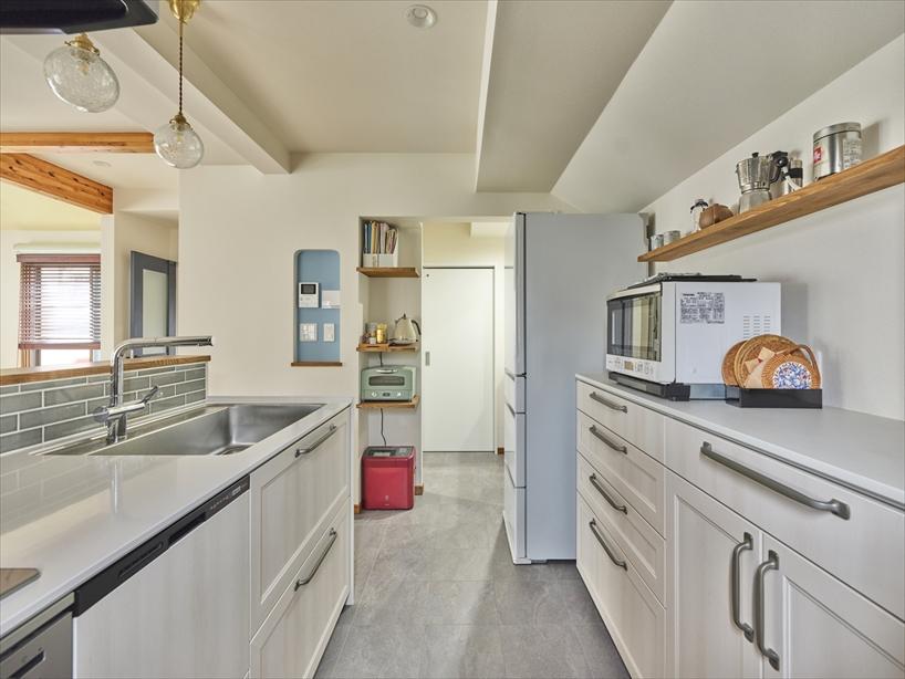 キッチンも対面式のレイアウトは変えずに設備を一新しました。背面にオープンシェルフをプラスしたり、ウォークスルー収納の入り口に家電棚を設けたりと、使い勝手に合わせて収納を充実させています。