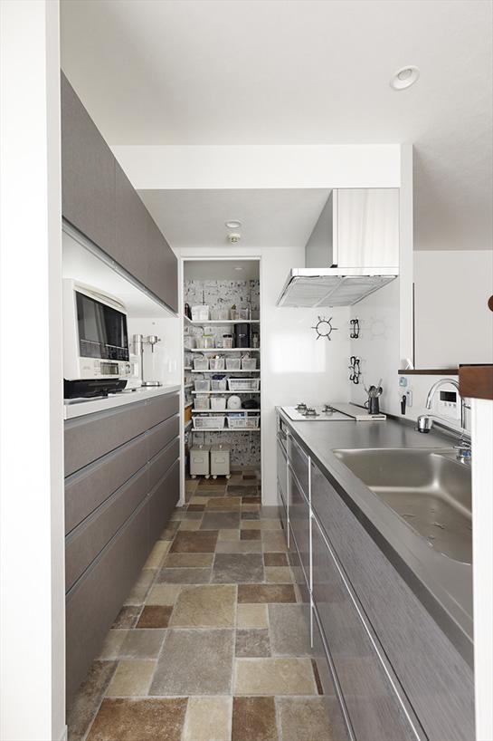 キッチンカウンター側面には開閉ができるワークスペースを造作し、配膳や片付けの時に便利。床は石畳風の長尺シートに。