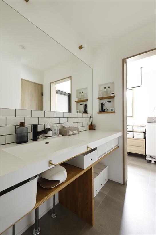 洗面スペースはオープンにし、すっきりしたカウンターにタイルを組み合わせて清潔感あるデザインに。奥はランドリースペースに。