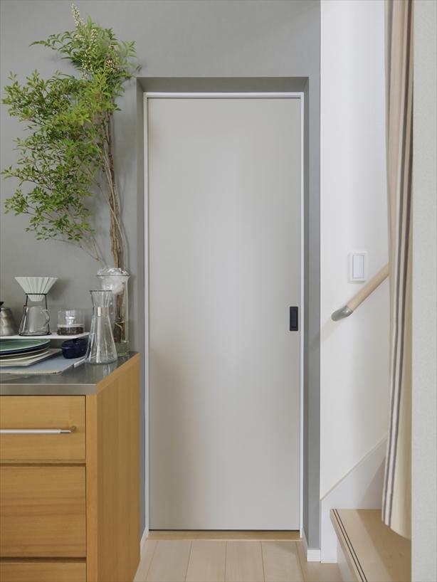 出入口は開きドアから引き戸に変え、それにともなってキッチンのクロスを張り替えました。グレージュの引き戸とグレーのアクセントクロスで、キッチンがよりシンプルモダンな雰囲気になりました。