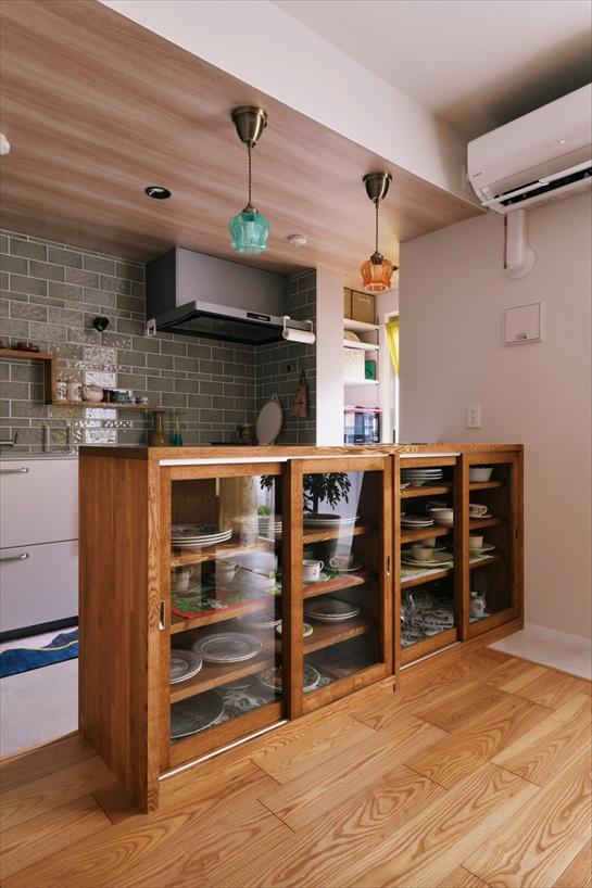 タモ集成材で造作したキッチンカウンター兼食器棚は、食器のコレクションを眺めて楽しめるようにガラス扉に。裏側も扉になっているので、キッチン側からも出し入れできます。