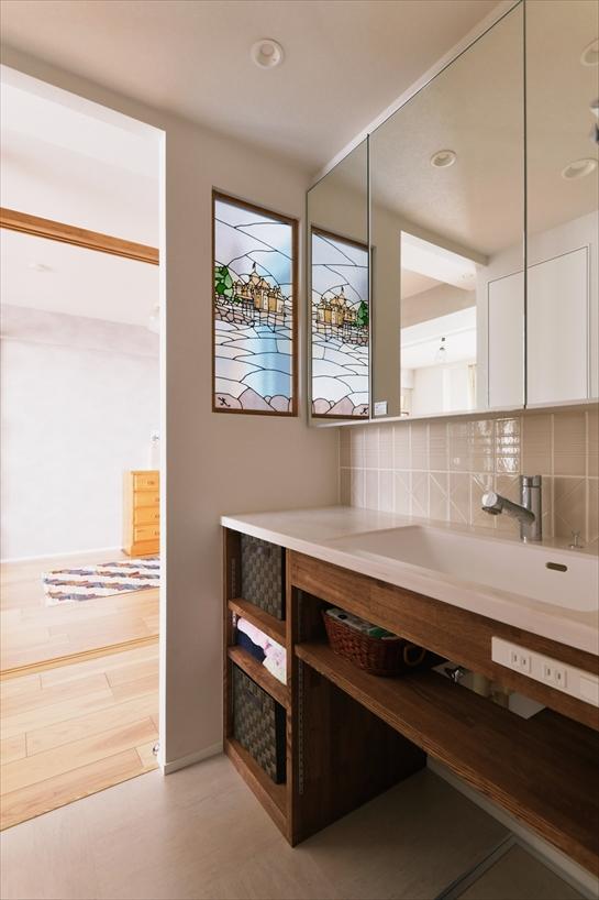 洗面室は脱衣室と分け、リビング側の扉をなくして動線をスムーズにしました。リビングから見える洗面台はタモ集成材で造作し、ナチュラルな雰囲気を演出。カウンター横のステンドグラスは、お二人の思い出であるスイスのシヨン城をモチーフに、写真をもとに下絵を作成して専門業者にオーダーしました。