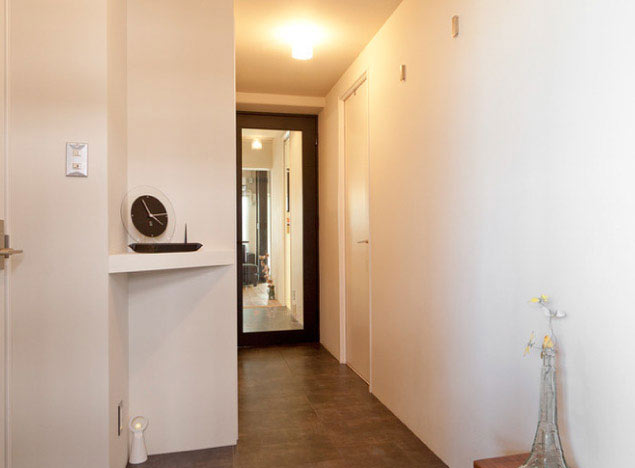 白い壁と黒っぽいPタイルがクールな印象の玄関